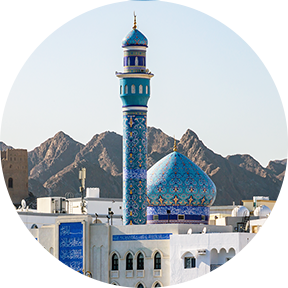Blaue Kuppel und Minarett der Mutrah-Moschee mit Berg im Hintergrund